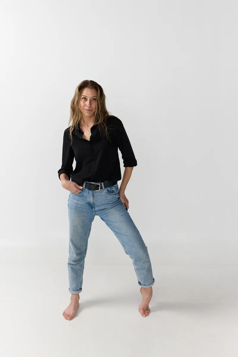 Jenna Stein standing in a black blouse and blue jeans