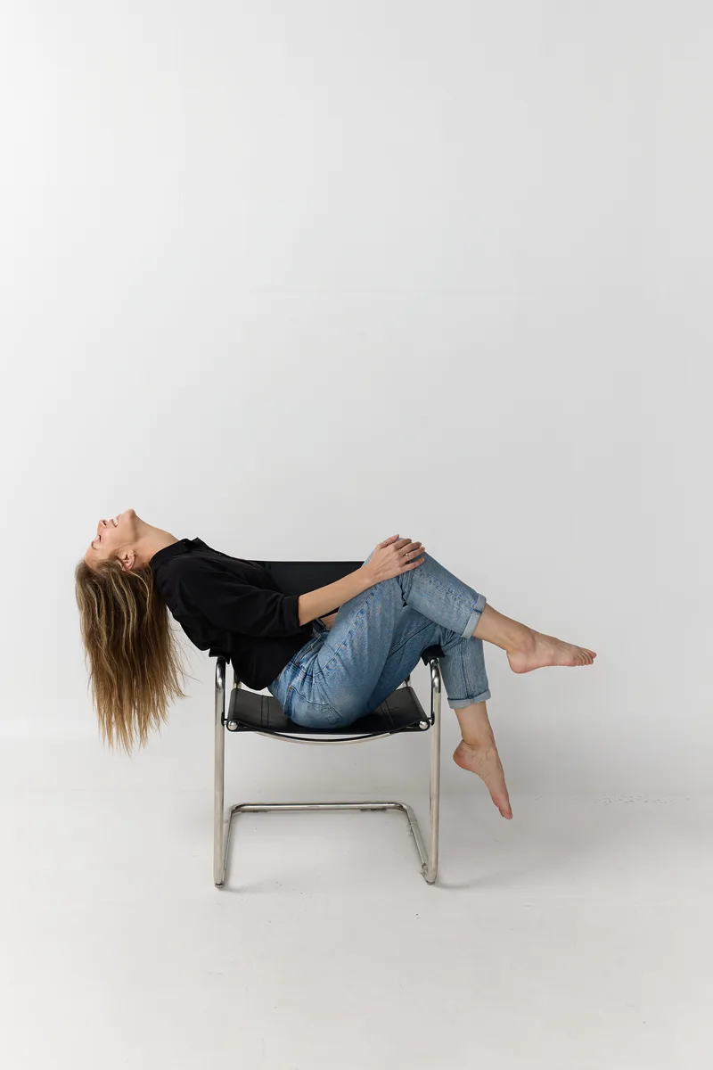 Jenna Stein reclining in a black chair wearing a black blouse and jeans
